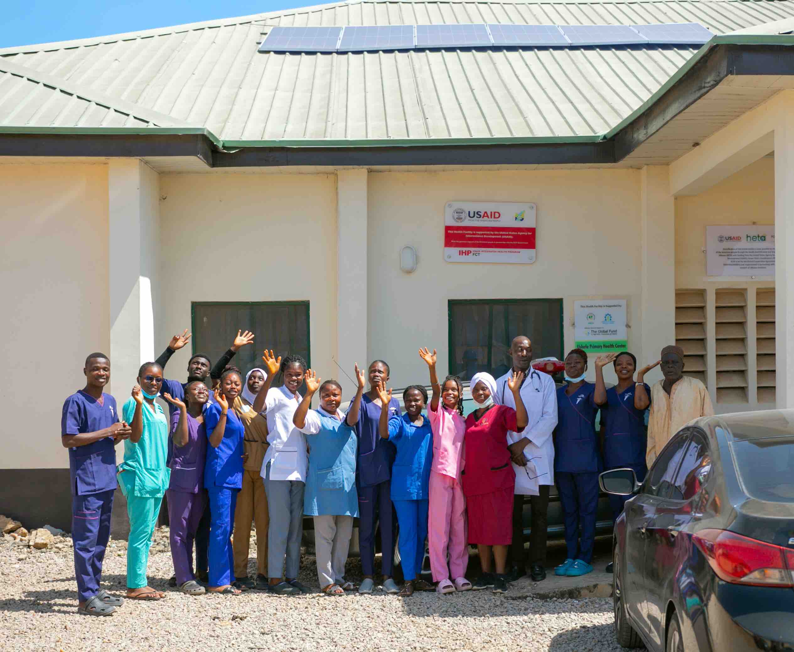 Health care workers smile and wave in front of solar powered clinic